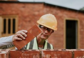 woman-contactor-laying-bricks-outside-home woman-contactor-laying-bricks-outside-home